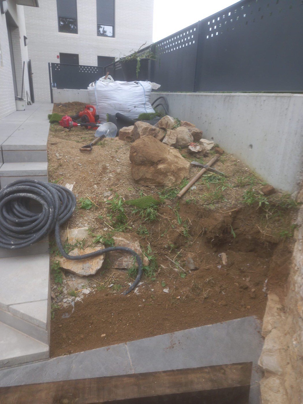 Talús de terra amb pedres i eines abans de començar l'obra